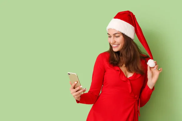 Schöne Junge Frau Mit Weihnachtsmütze Und Handy Auf Farbigem Hintergrund — Stockfoto