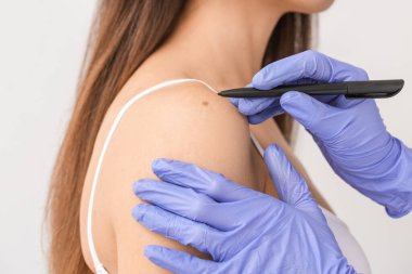 Dermatolog, hafif arka plandaki hastayı muayene ediyor. Yakın plan.