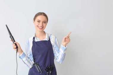 Kadın kuaför arka planda bir şey gösteriyor.