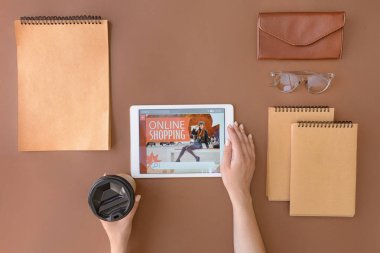 Tablet bilgisayarlı bir kadın çevrimiçi olarak renk arkaplanı ve üst görünümü üzerinden alışveriş yapıyor.