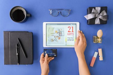 Tablet bilgisayarlı bir kadın çevrimiçi olarak renk arkaplanı ve üst görünümü üzerinden alışveriş yapıyor.
