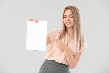 Açık arkaplanda boş kağıt kağıtları olan genç bir kadın.