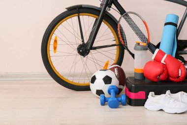 Işık duvarının yanında bisikleti olan spor aletleri.