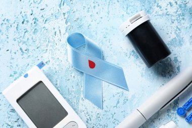 Renk arkaplanında glukometre ve tükenmez kalemle farkındalık kurdelesi. Diyabet kavramı