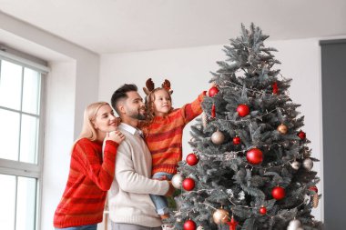 Evde Noel ağacı süsleyen genç bir aile.