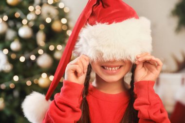 Evde Noel Baba şapkası takan komik küçük kız.