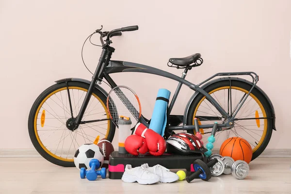 Set of sport equipment with bicycle near light wall