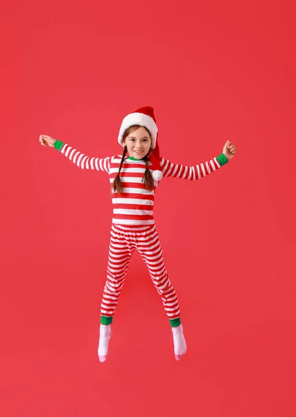 Springendes Kleines Mädchen Mit Nikolausmütze Auf Farbigem Hintergrund — Stockfoto