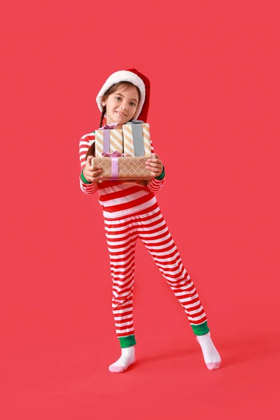 Nettes Kleines Mädchen Mit Nikolausmütze Und Weihnachtsgeschenken Auf Farbigem Hintergrund — Stockfoto