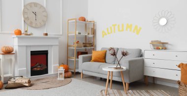 Beyaz şöminesi, sehpası, rahat kanepesi ve saati olan bir oturma odası.