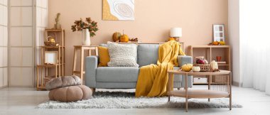 Sonbahar dekoru, kanepesi ve masası olan rahat bir oturma odası.