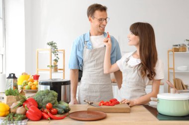 Genç çift mutfakta dolmalık biber kesiyor.