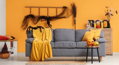 Cadılar Bayramı için dekore edilmiş oturma odasının içi kanepe, merdiven ve balkabağıyla süslenmiş.