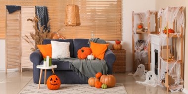 İçinde mavi kanepe, şömine ve farklı Cadılar Bayramı süslemeleri olan festival salonu.