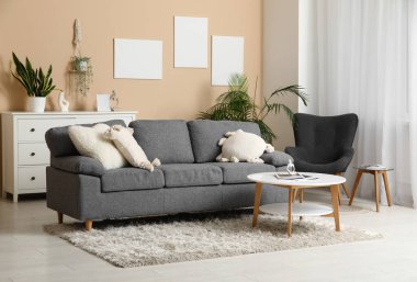 Oturma odasının iç tarafında minderli, koltuklu ve sehpalı rahat bir kanepe.