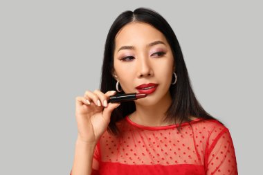 Gri arkaplanda ruj izi olan güzel bir Asyalı kadın.