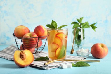 Lezzetli şeftalili buzlu çay ve mavi grunge arkaplanda malzemelerle yakın plan kompozisyonu.