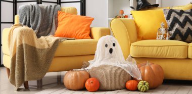 Cadılar Bayramı balkabakları ve hayalet sarı kanepenin yanında.