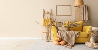 Sarı kanepe, balkabakları, otlar ve ekoseler sonbaharda oturma odasının içinde.