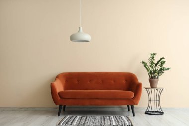 Kırmızı kanepe, bitki ve lambalı şık bir oturma odası.