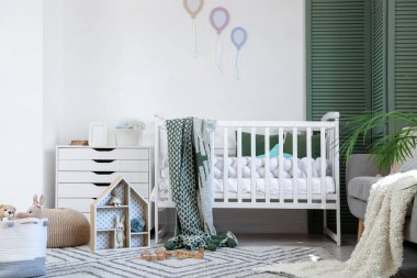 Interior of nursery with crib, toys and folding screen