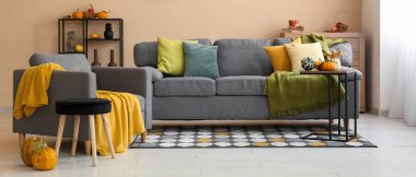 Sonbahar dekoru, kanepesi ve koltuğu olan rahat bir oturma odası.