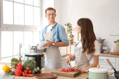 Young couple cooking at table in kitchen
