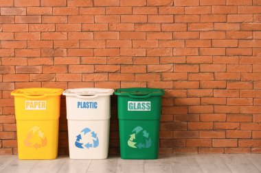 Tuğla duvarın yanındaki farklı çöp kutuları için boş çöp kutuları. Geri dönüşüm kavramı