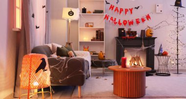 Gri kanepesi, şöminesi ve Cadılar Bayramı süslemeleri olan karanlık oturma odasının içinde.