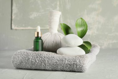 Kaplıca taşları, yeşil yapraklar, bitkisel poşet ve yeşil grunge arka planda bir şişe kozmetik ürünü, yakın plan