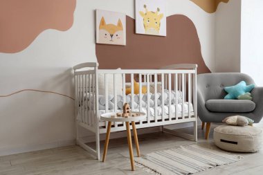 Interior of nursery with crib, table and armchair
