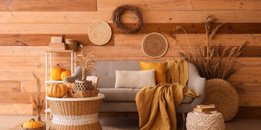 Oturma odasının sonbaharında rahat bir kanepe, ekose, balkabağı ve kahve masası.