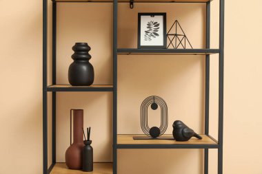 Bej duvarın yanında şık dekorlu siyah raf ünitesi