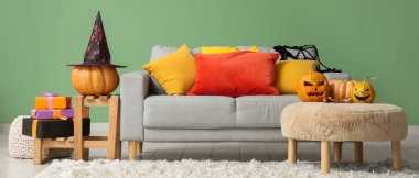 İçinde kanepe, Cadılar Bayramı balkabağı ve hediyeler olan bir oturma odası.