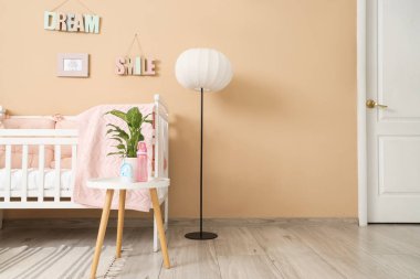 Interior of nursery with crib, table and lamp