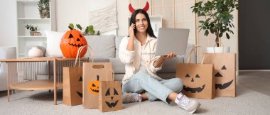 Şeytan boynuzları içinde genç bir kadın Cadılar Bayramı için internette alışveriş yapıyor.