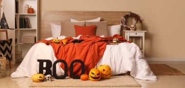 Yatak odasının içi Cadılar Bayramı için raf ünitesi, masa ve balkabaklarıyla dekore edilmiş.