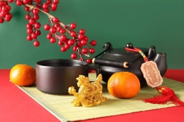 Altın ejder heykelciği ve yeşil arka planda mandalinalı geleneksel çay seti. Çin Yeni Yıl Kutlaması