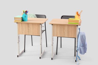 Sırt çantalı, kitaplı ve gri arkaplanlı modern okul sıraları