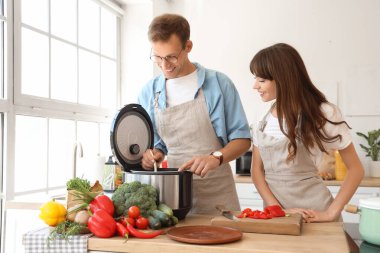 Genç çift mutfakta çoklu fırın kullanıyor.