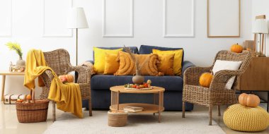 Sonbahar dekoru, kanepesi ve hasır koltukları olan bir oturma odası.