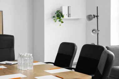 Konferans salonunda yapılacak iş görüşmesi için hazırlanmış su ve kağıt kağıtlarla dolu bir masa.