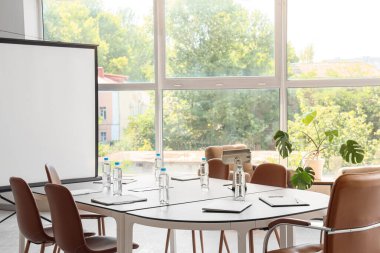 Interior of conference hall with table, projector screen and window