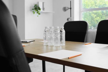 Konferans salonunda yapılacak iş görüşmesi için hazırlanmış su ve kağıt kağıtlarla dolu bir masa.