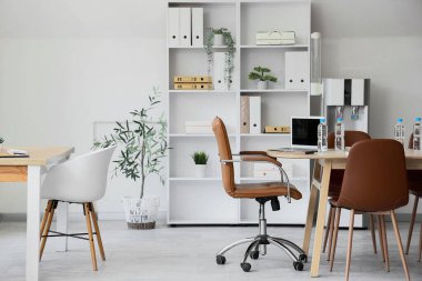 Interior of conference hall with desks, shelf unit and water cooler