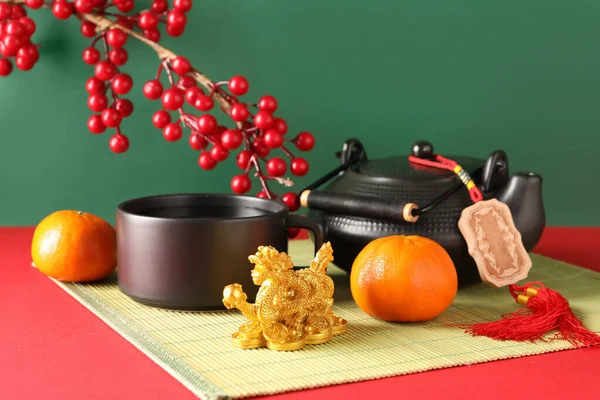 Altın ejder heykelciği ve yeşil arka planda mandalinalı geleneksel çay seti. Çin Yeni Yıl Kutlaması