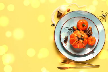 Sarı arka planda balkabakları ve örümceklerle Cadılar Bayramı sofrası