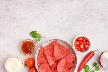 Kırmızı nachos, sebze ve soslu kase beyaz grunge arka planda.