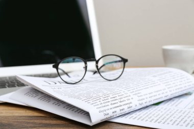 Newspapers with glasses on wooden table