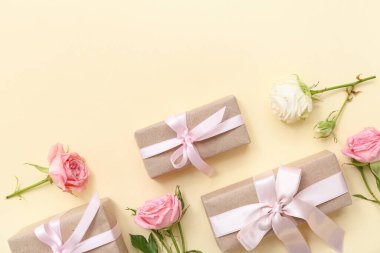 Zarif paketlenmiş hediye kutuları ve bej arka planda gül çiçekleri